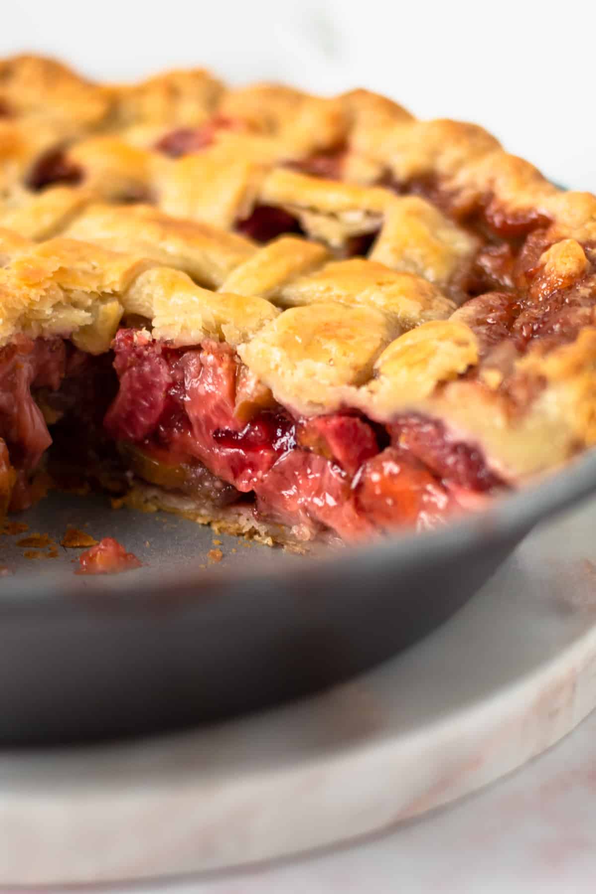 A baked strawberry Rhubarb pie with a slice taken out of it in the pie tin.