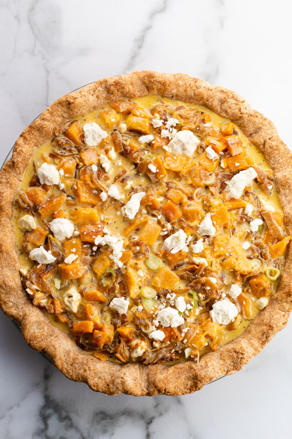 An assembled but unbaked savory butternut squash with feta pie.