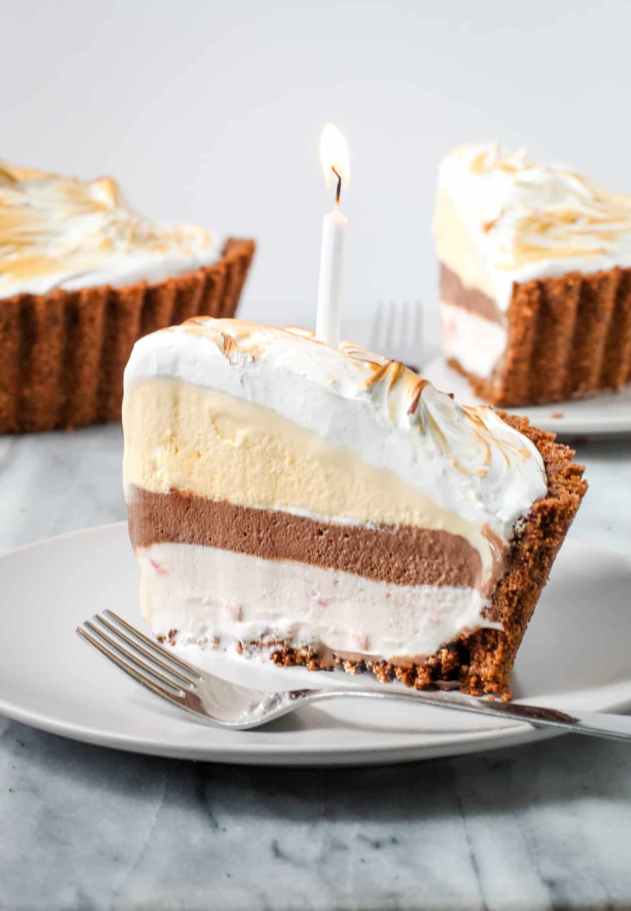 Slice of Neopolitan Baked Alaska with a candle in it