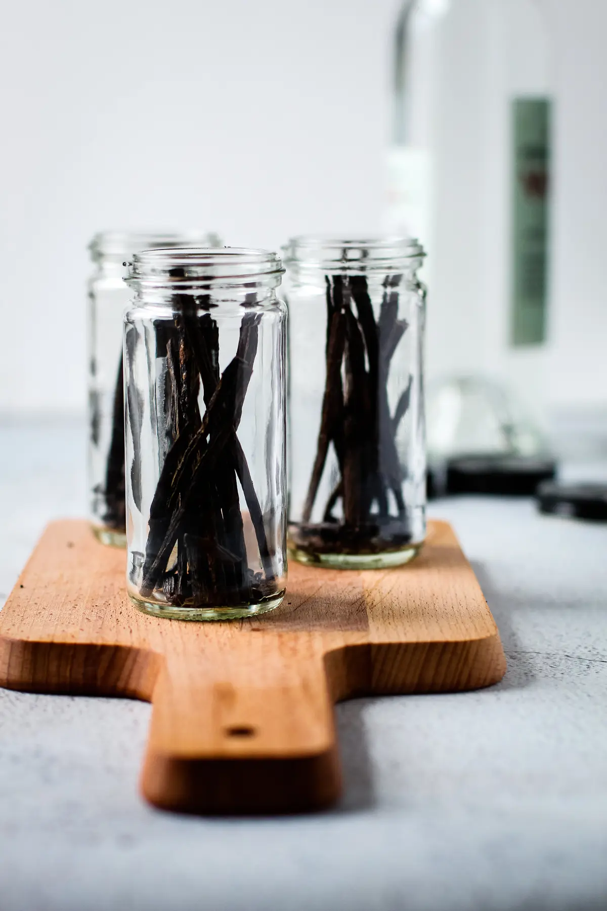 Three clear jars with sliced vanilla beans in them to make extract