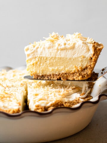 A slice of coconut cream pie being lifted from the pie plate.