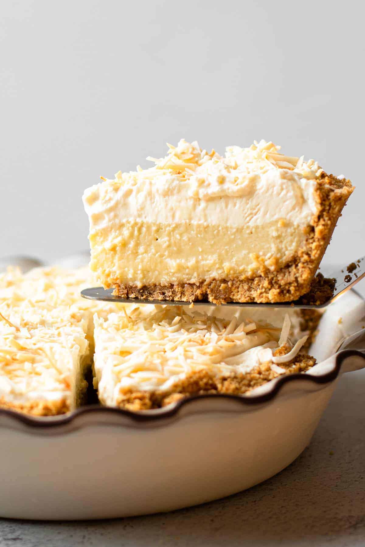 A slice of coconut cream pie being lifted from the pie plate.