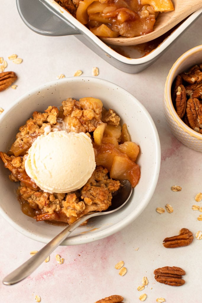 A bowl of apple crisp with vanilla ice cream on top.