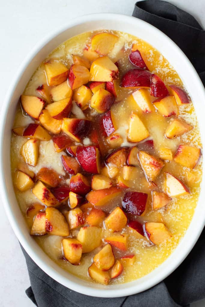 Peaches cobbler batter, melted butter and with fresh peaches on top.