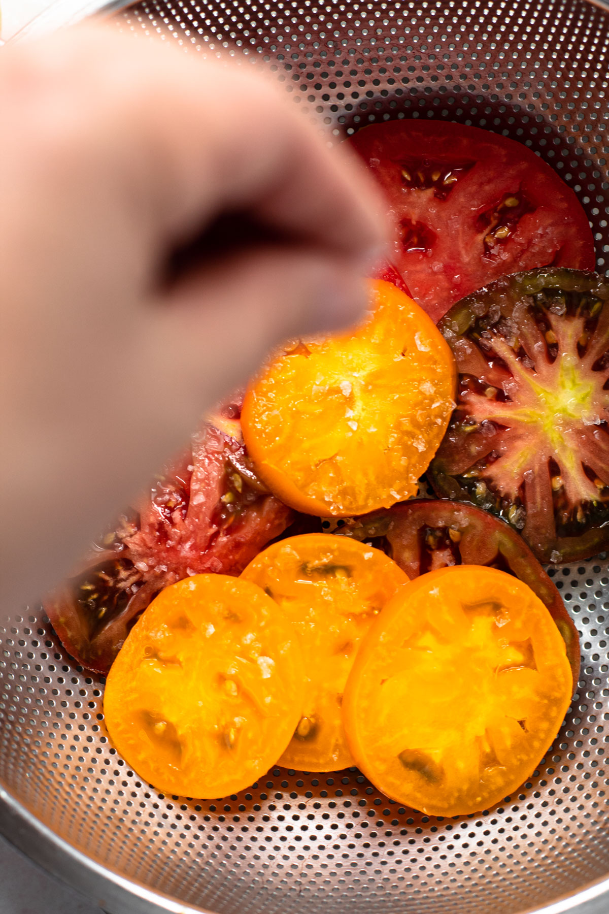 Sliced tomatoes being salted for a tomato galette.