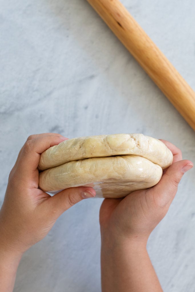 Two pie crusts wrapped in plastic wrap.