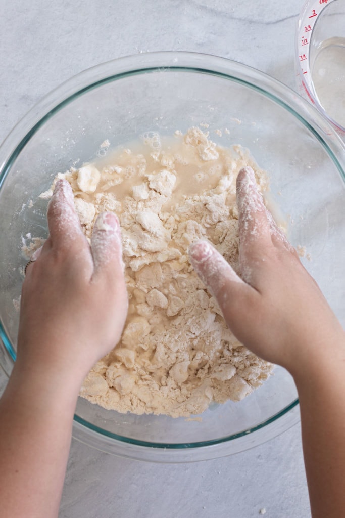 Gently combining homemade pie crust in a bowl.