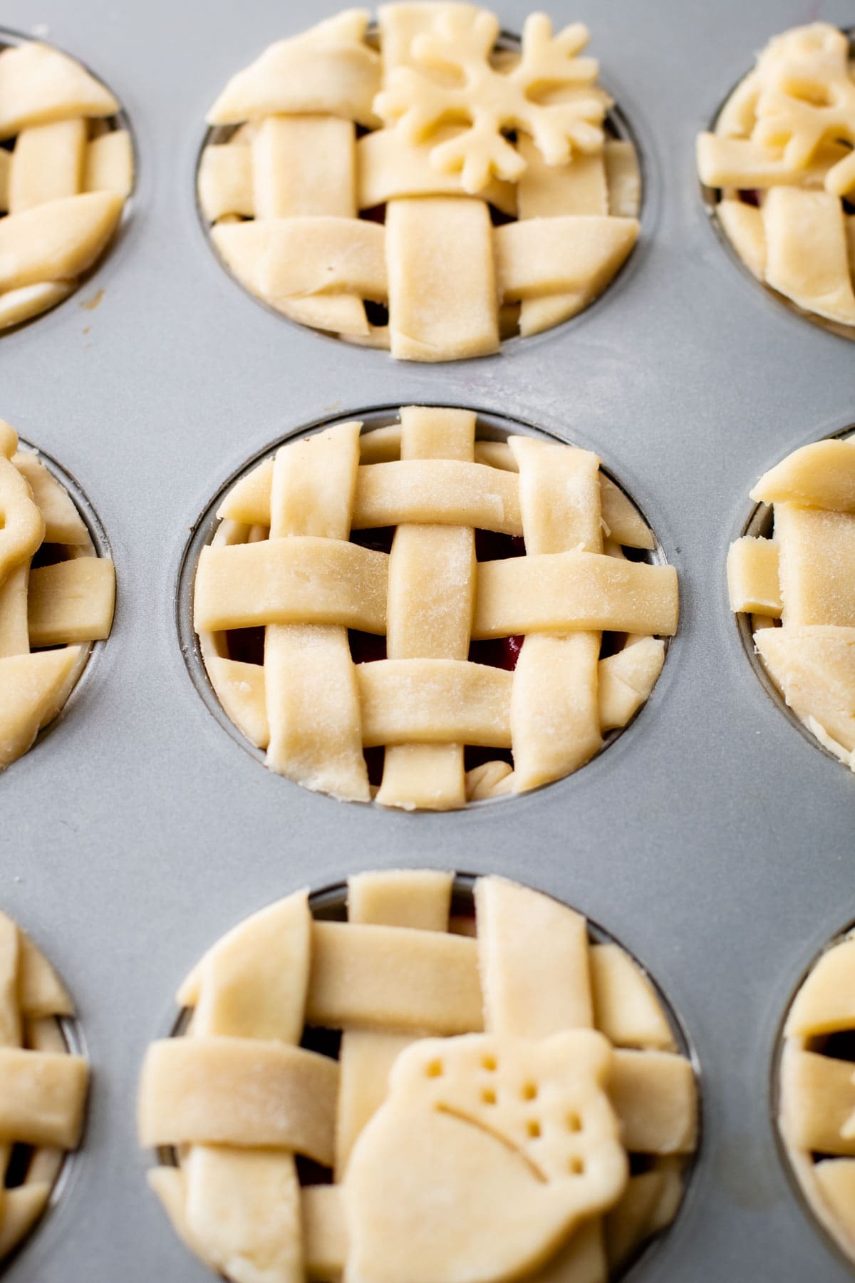 Mini cranberry pear pies unbaked in a muffin tin.