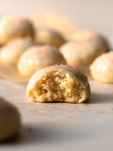 An Italian anise cookie with a glaze displayed with a bite taken out of it.