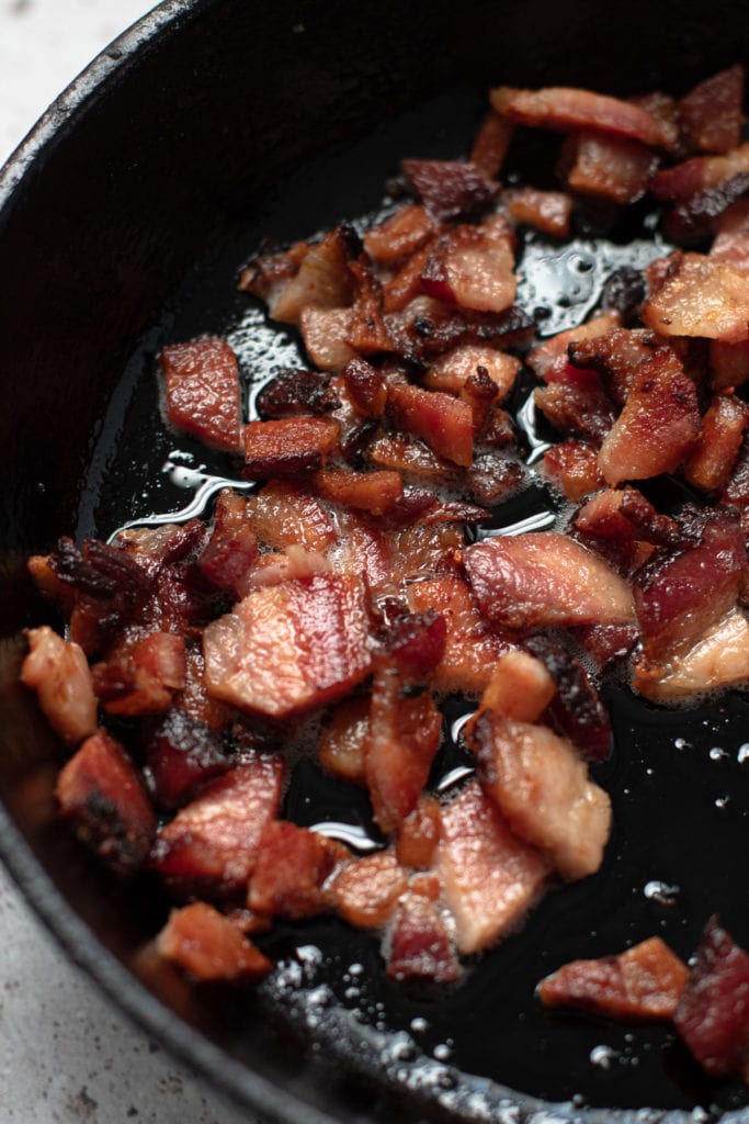 Crispy bacon in a skillet for quiche Lorraine.