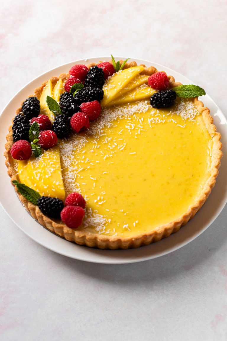 A coconut lime tart with a decorative ring of berries and fruit
