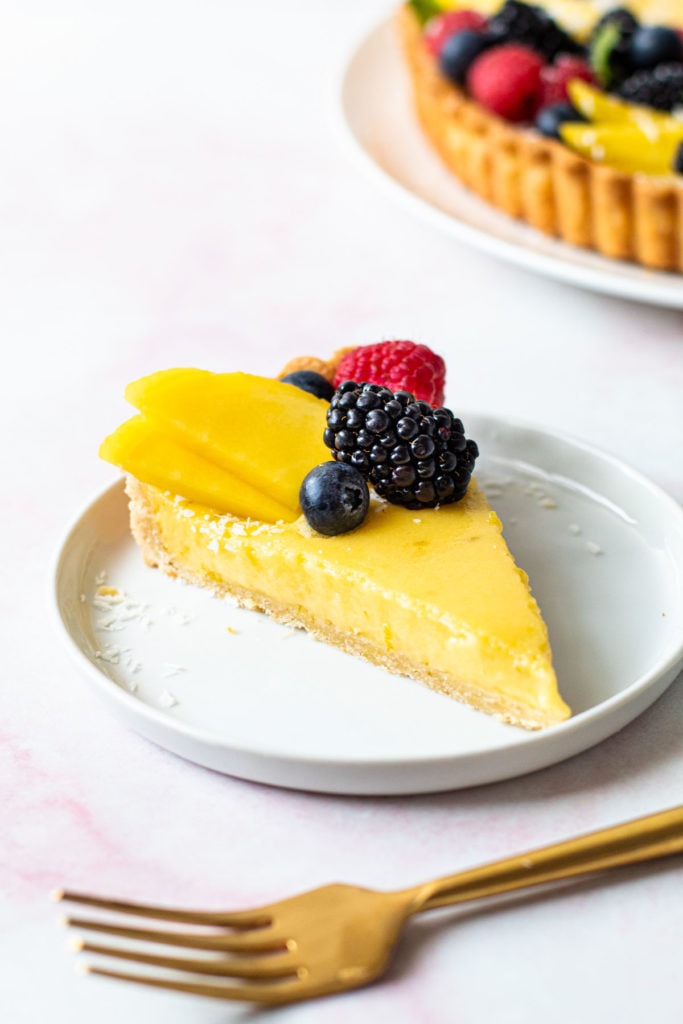 A slice of coconut lime tart with fruit on top.