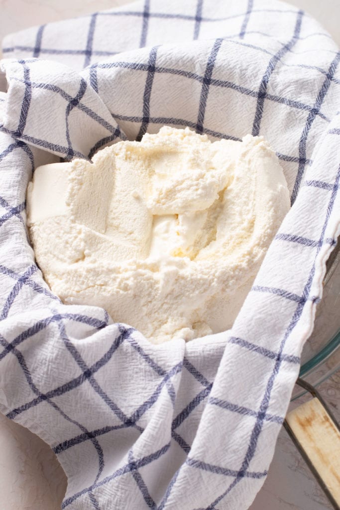 Ricotta draining in a strainer.