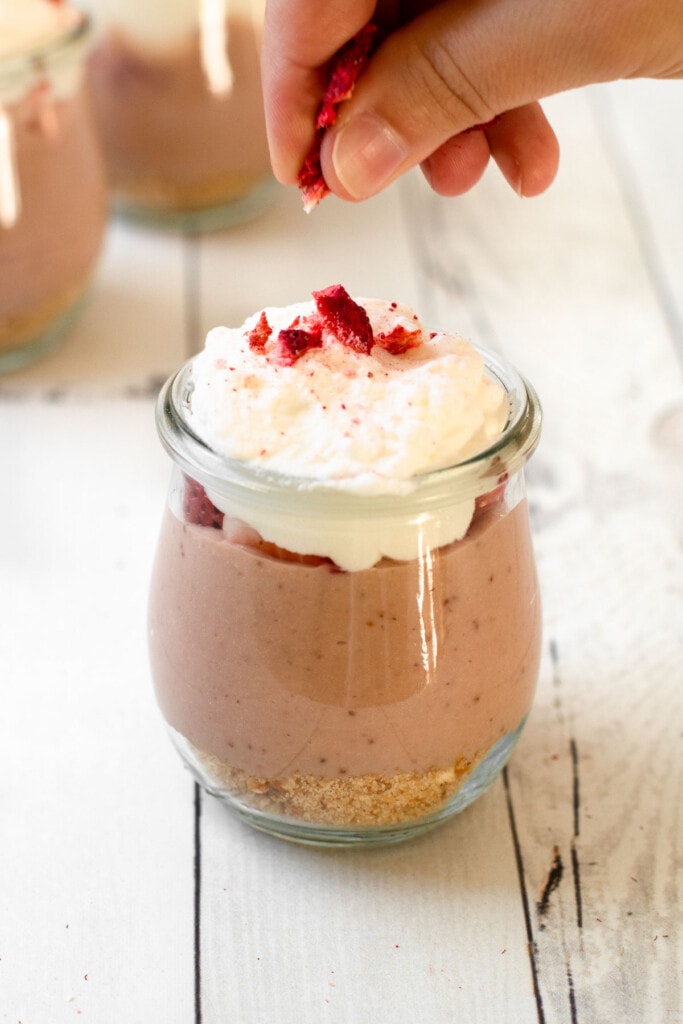 Whipped cream layer in a strawberry pudding pie jar.