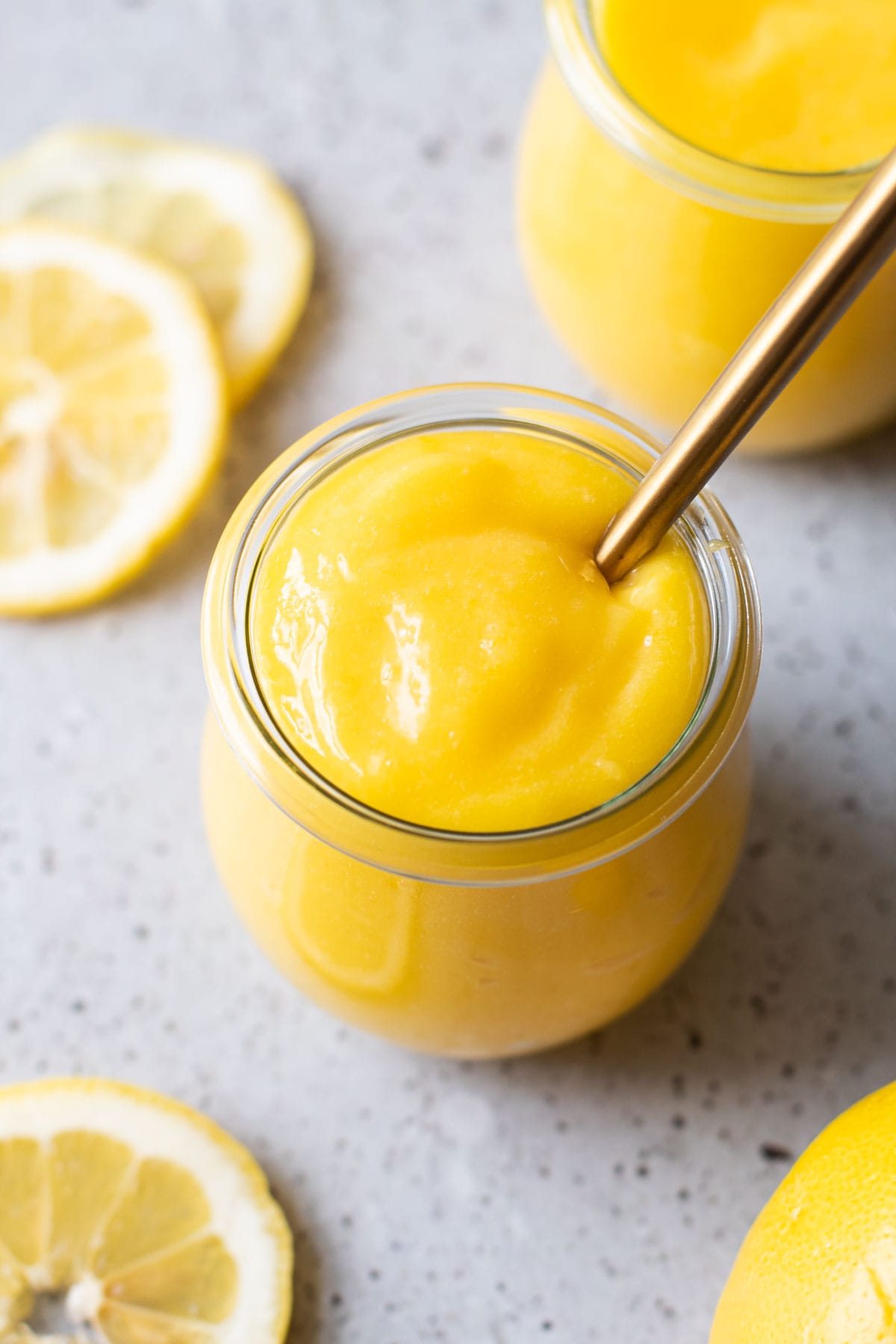 Homemade lemon curd in a small jar with a spoon in it.