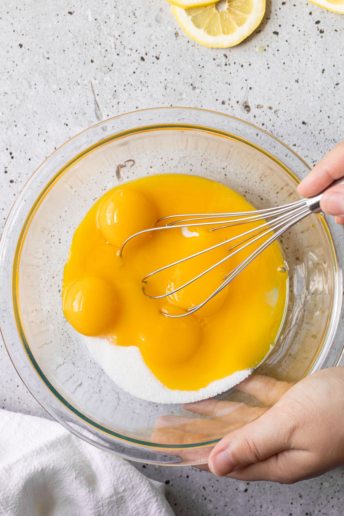 Egg yolks and sugar in a bowl for a lemon curd recipe.
