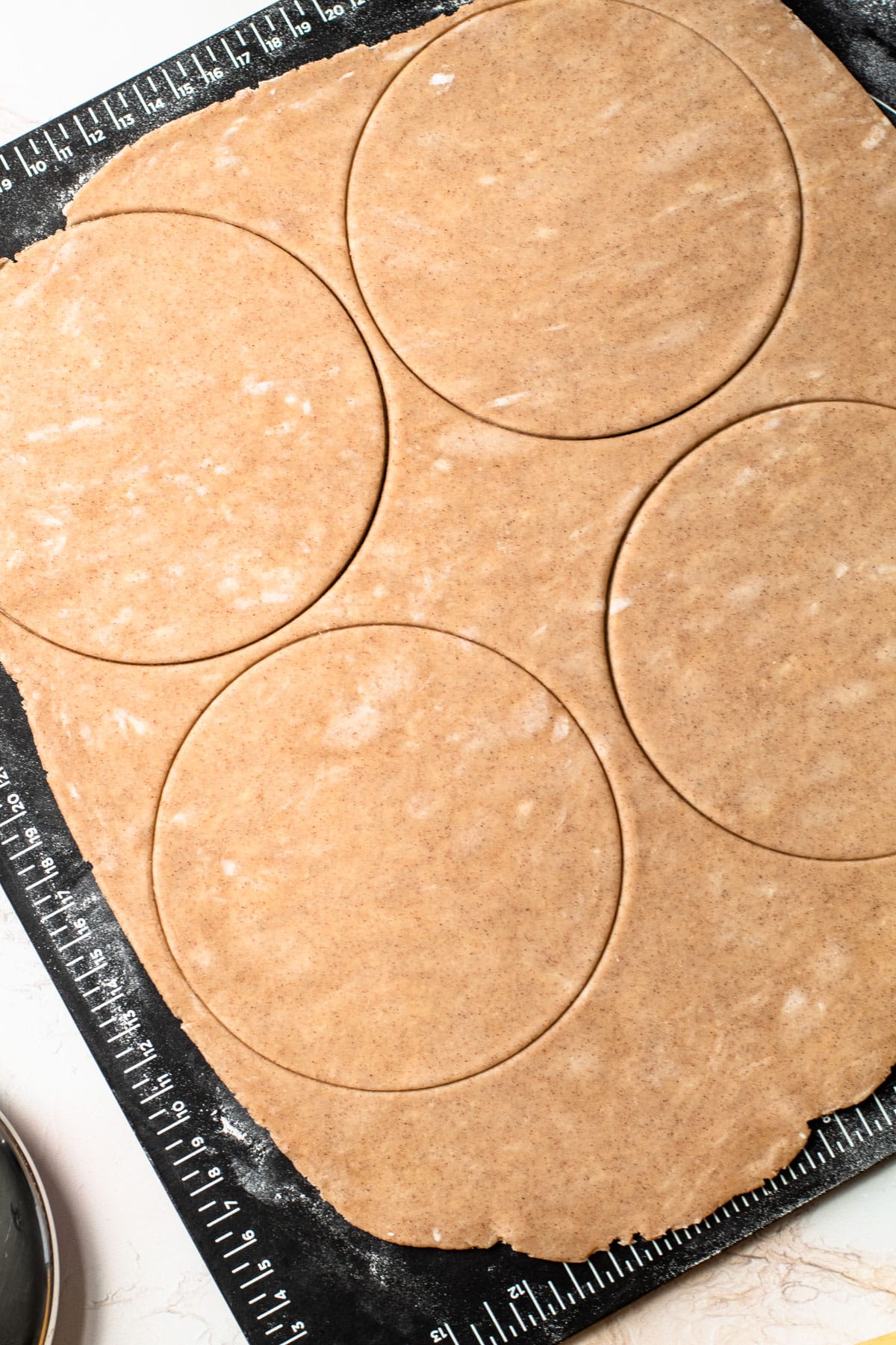 Dough for pumpkin pasties rolled out and stamped in a circle.