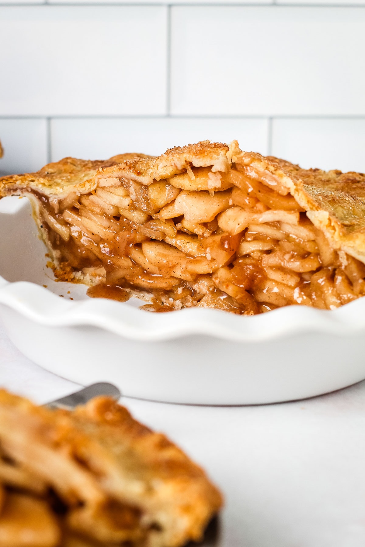 A mile high apple pie packed cut in half to reveal an apple packed pie.