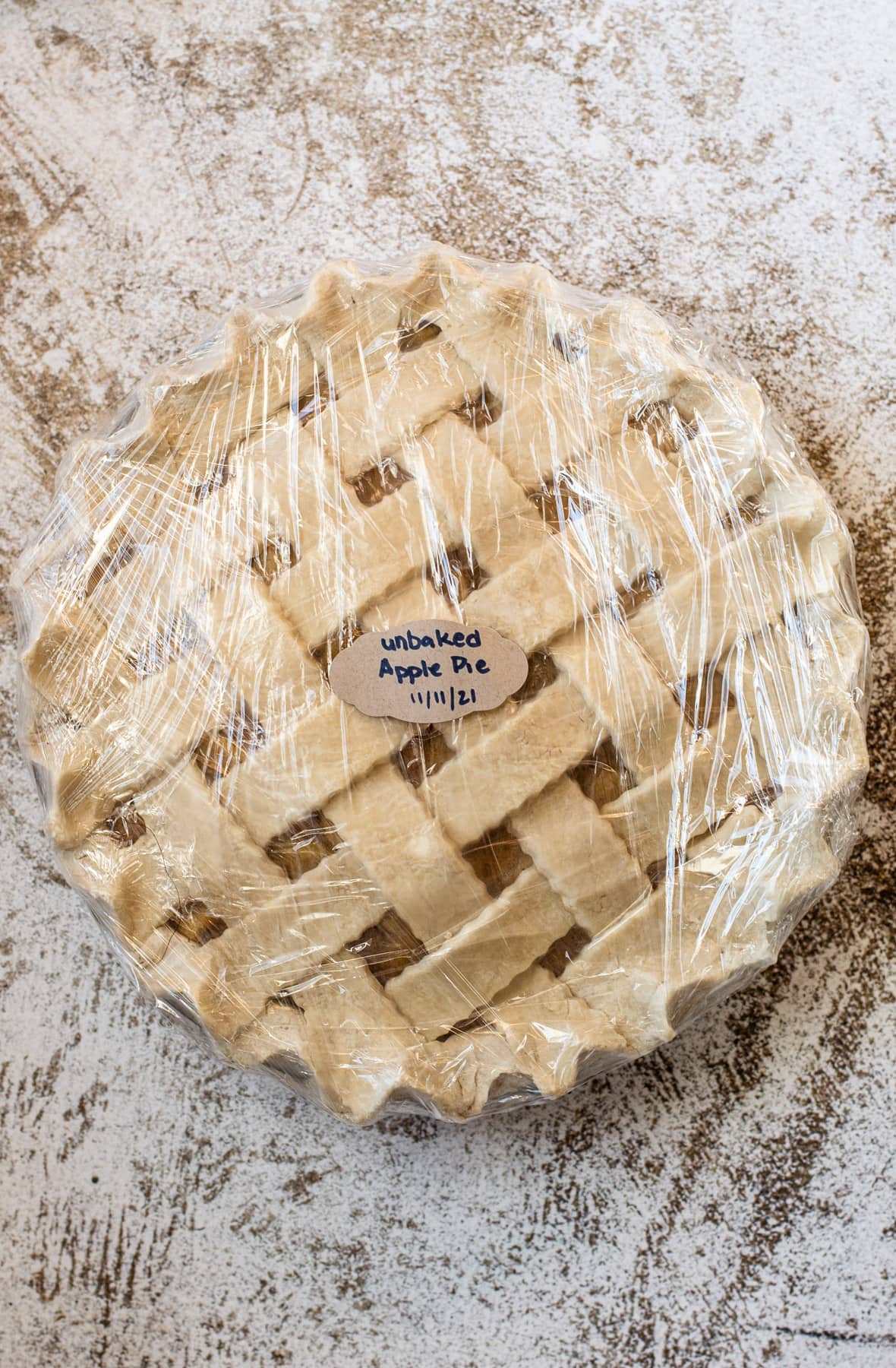 A frozen apple pie wrapped in plastic wrap and labelled.