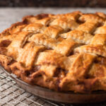 A double crust lattice apple pie cooling on a pie rack.
