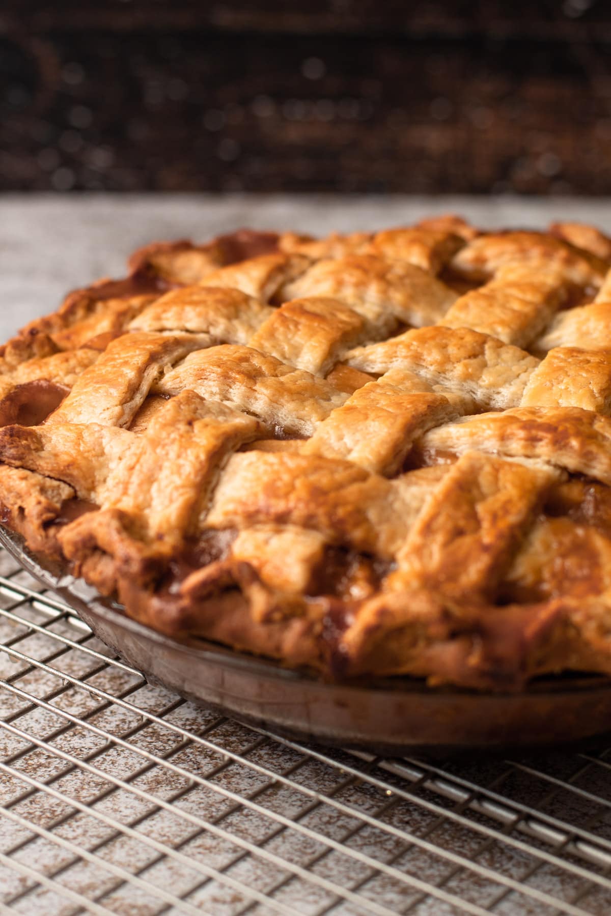 A double crust lattice apple pie cooling on a pie rack.