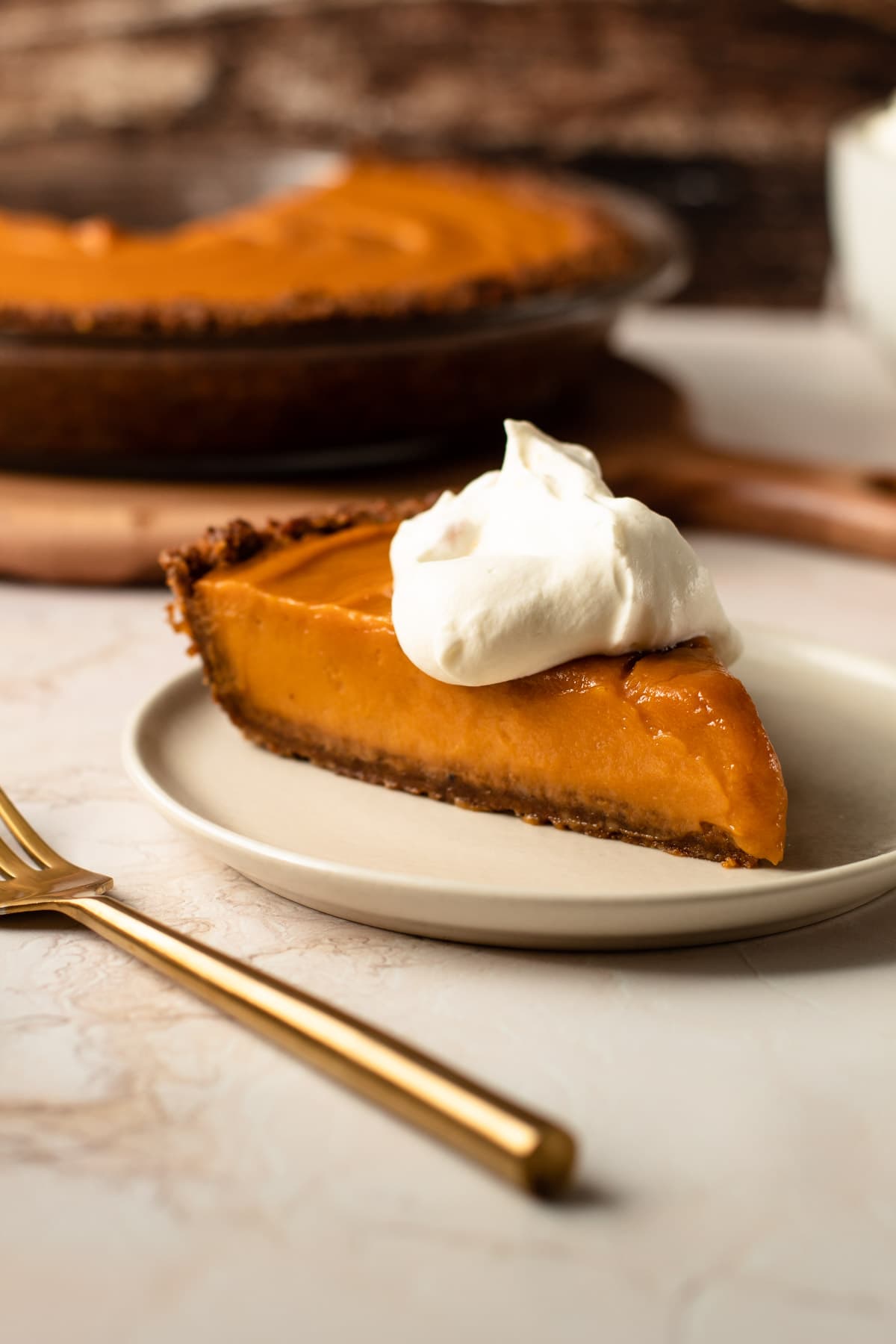 A slice of sweet potato pie with maple whipped cream on top.