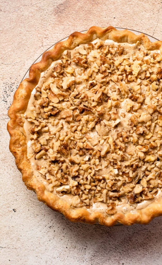 Unbaked walnut pie filling with walnuts sprinkled on top.