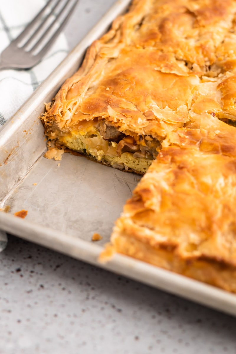 A slice of a breakfast slab pie removed to reveal bacon and eggs in a pastry crust.