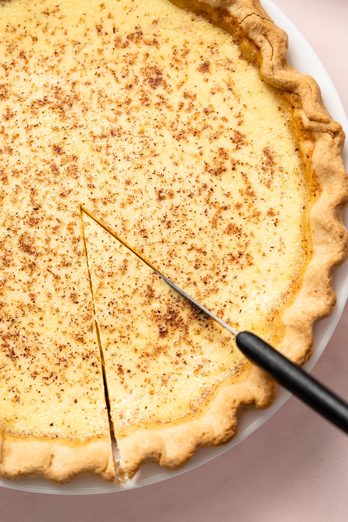 A knife slicing through a classic custard pie.