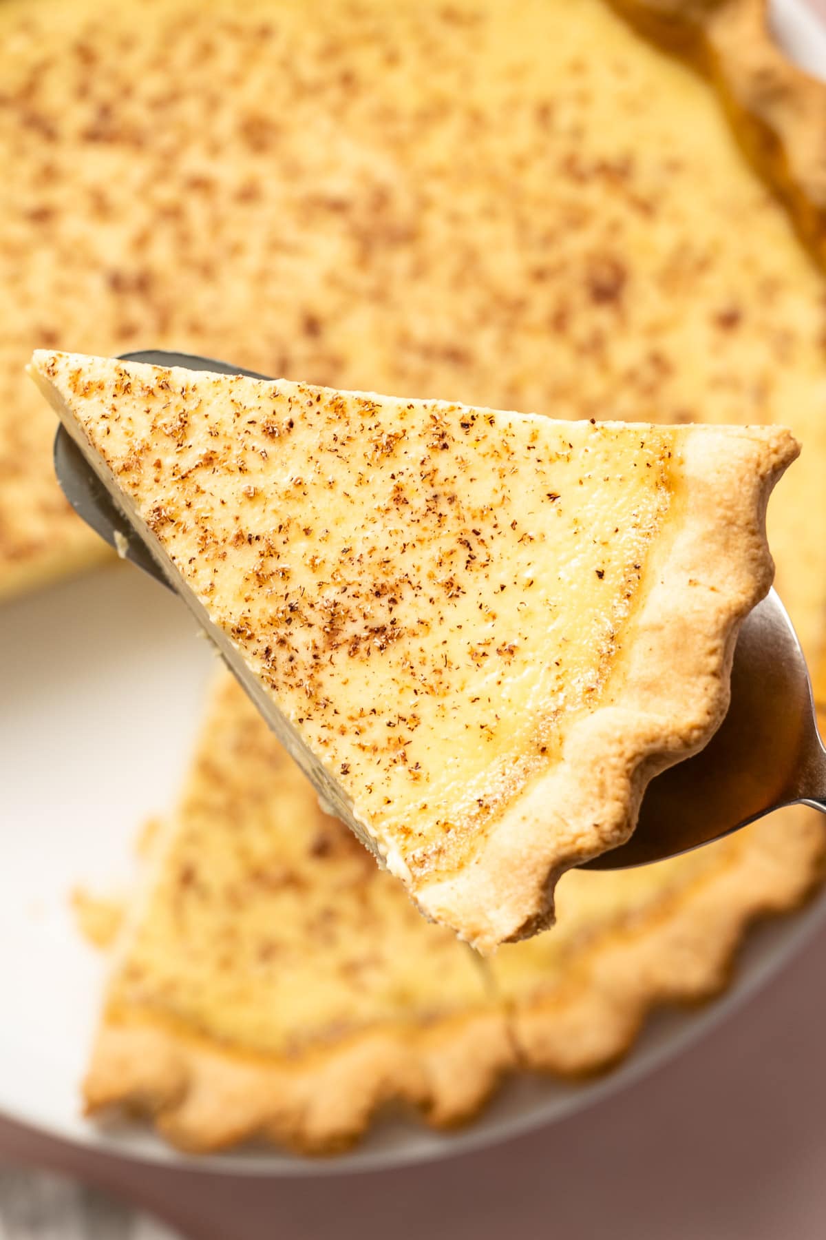 A slice of custard pie on a pie server.