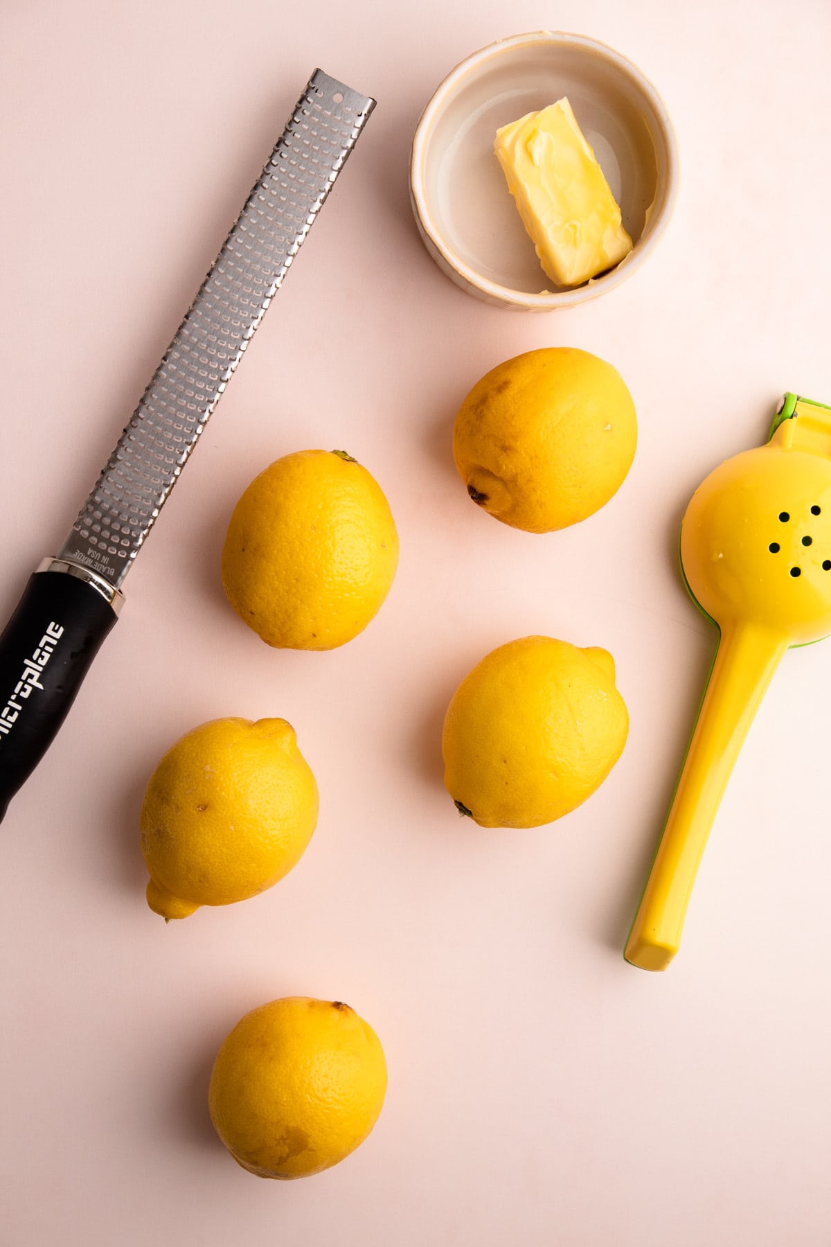 Lemons next to a zester and a juicer.