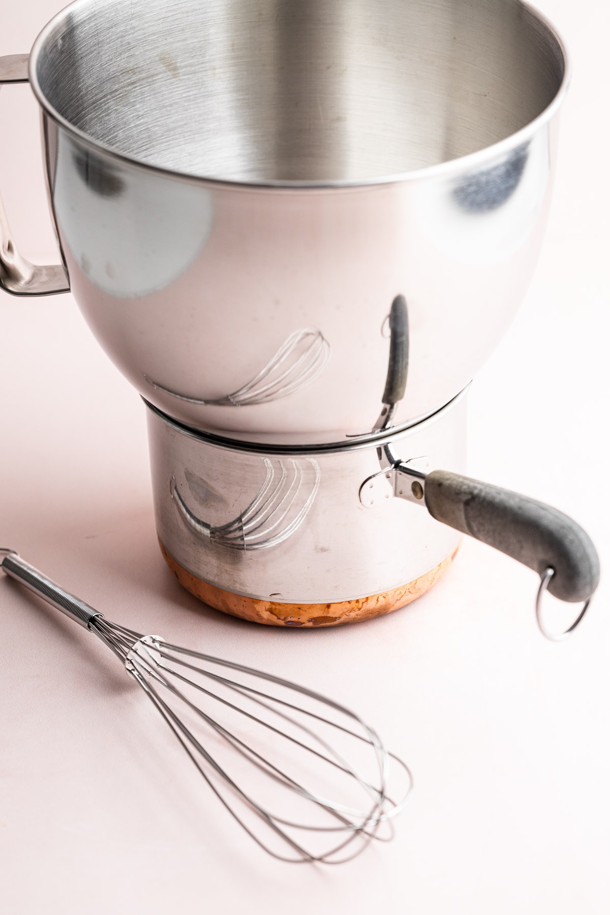 A kitchen aid mixing stainless steel mixing bowl on top of a small pot.