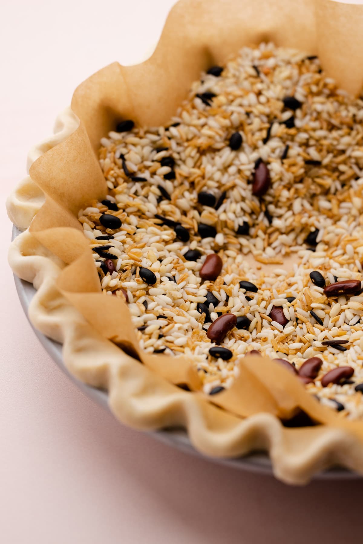 An unbaked pie crust with parchment and pie weights inside.