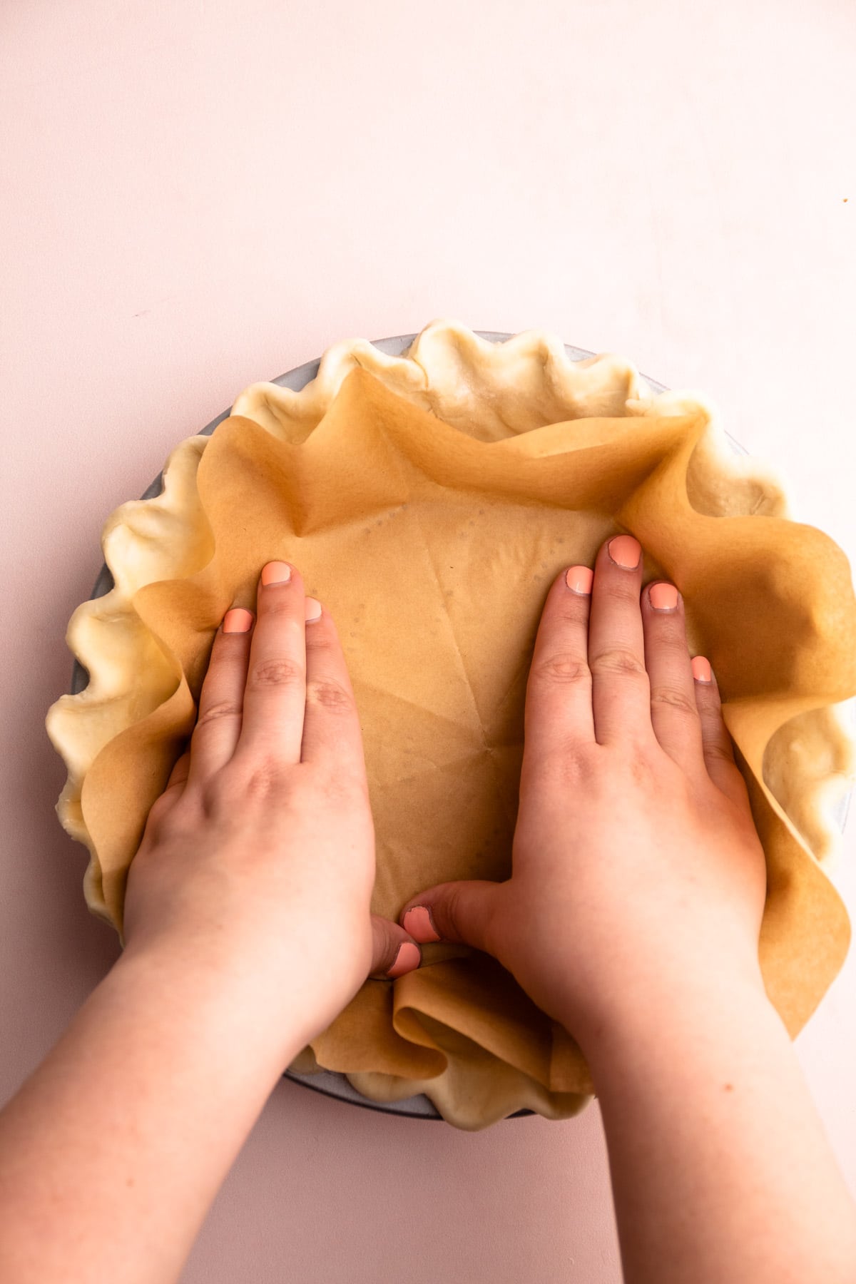 Putting parchment into the pie crust for blind baking.