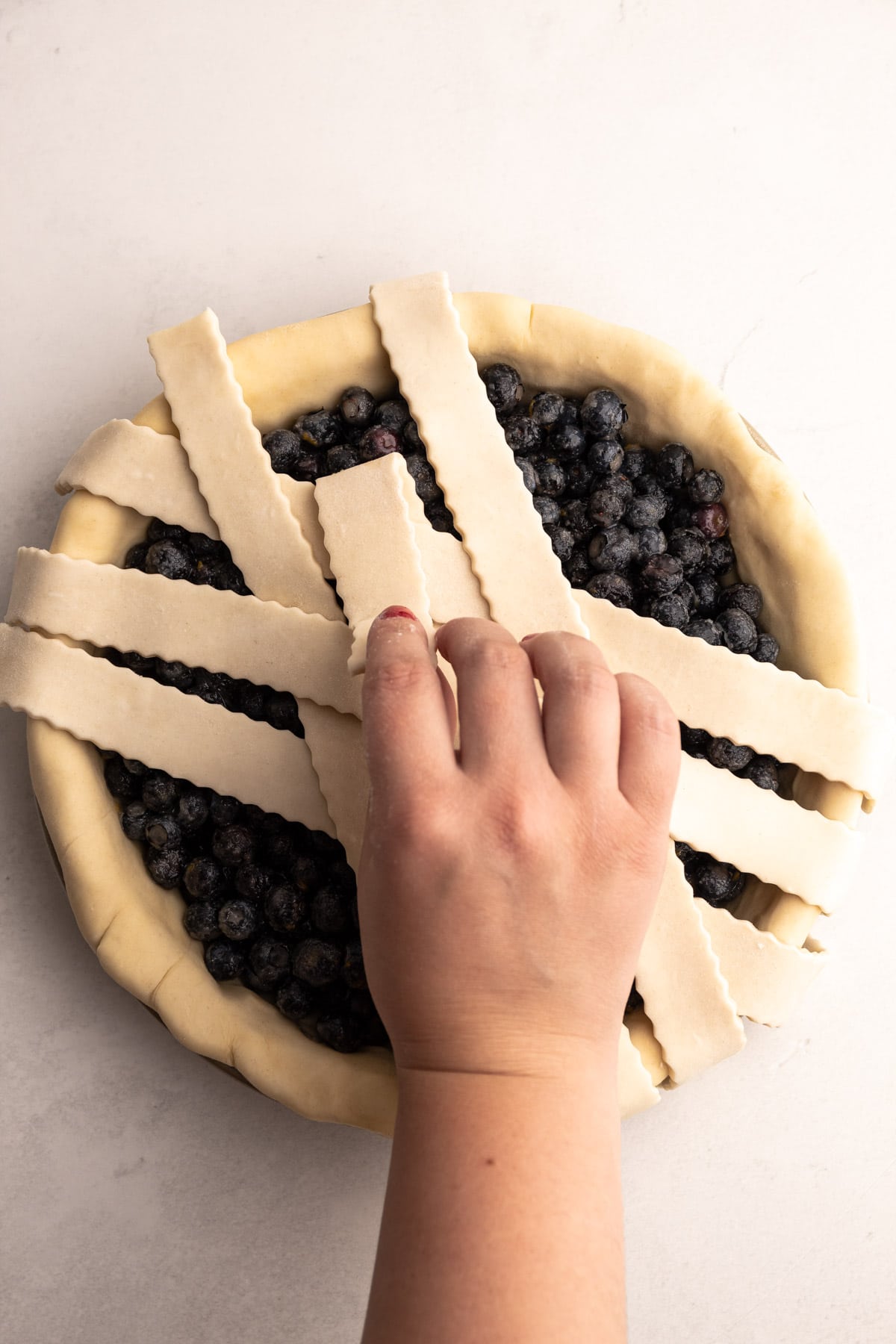 Putting a lattice on a blueberry pie crust.