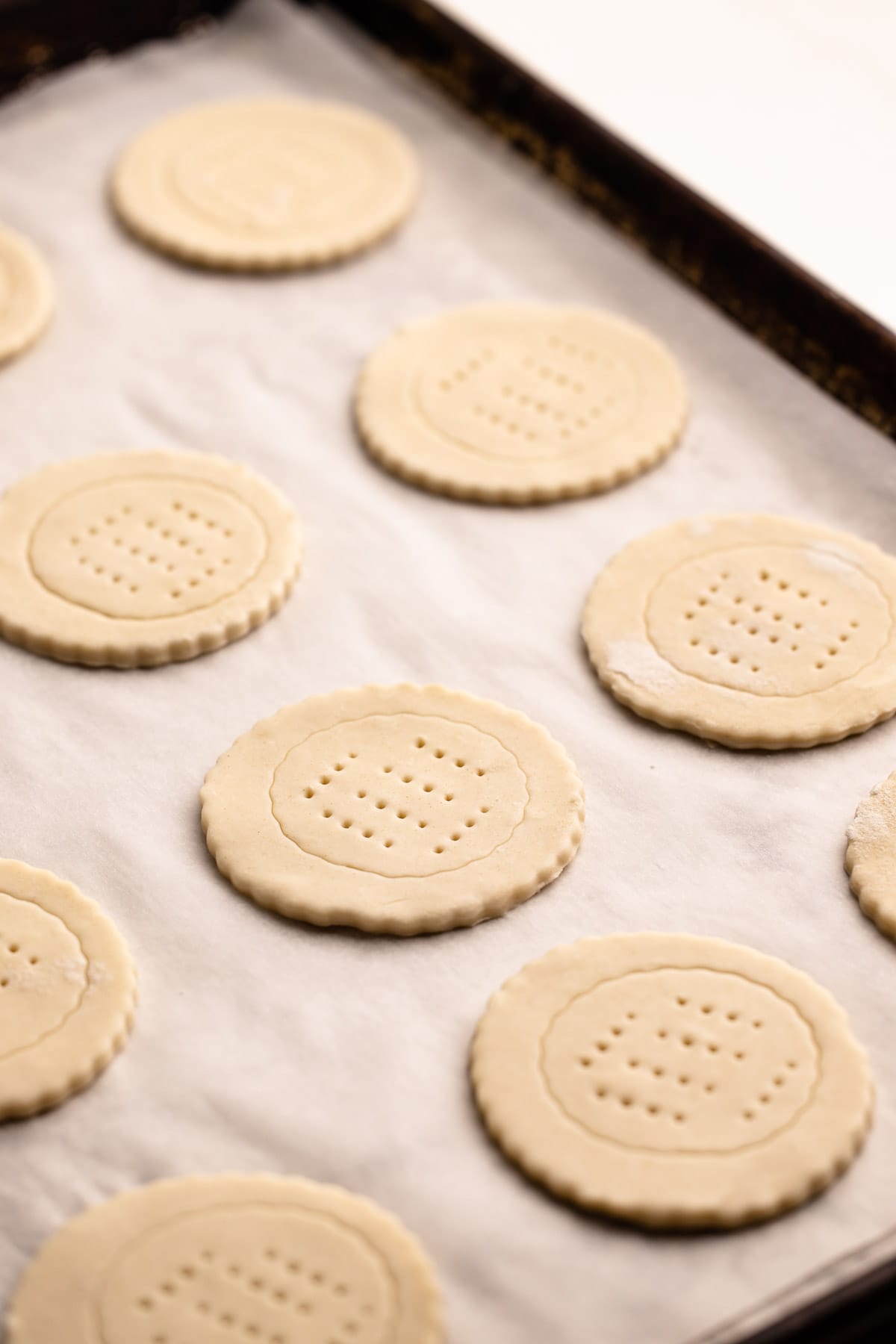 Circles of puff pastry with fork marks docked in the middle.