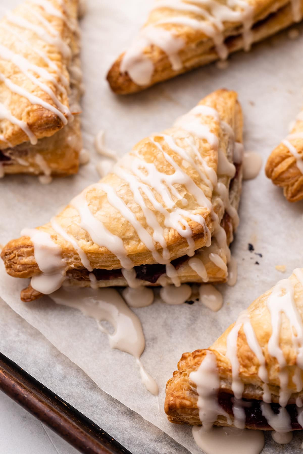 Cherry Turnovers on a sheet pan with a vanilla glaze.