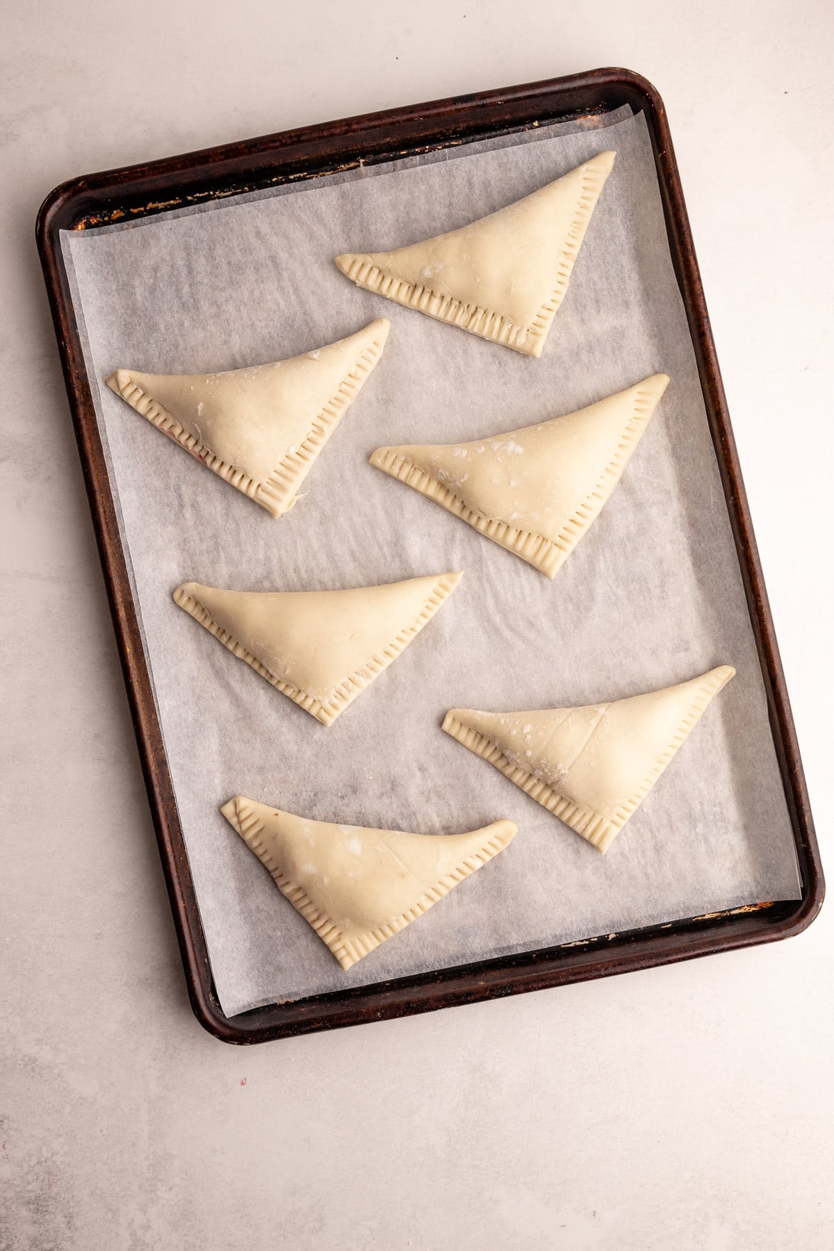 Turnovers unbaked on a sheet tray.