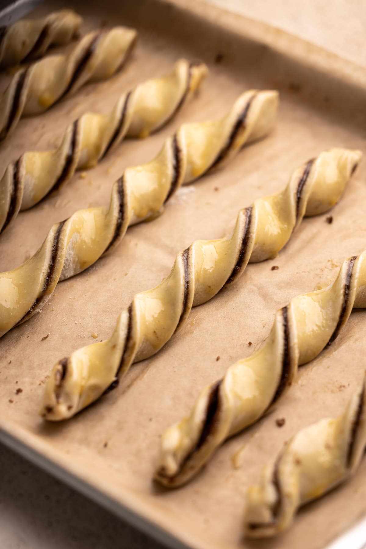 Cinnamon twists on a baking sheet with egg wash.