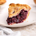 A slice of blackberry pie on a plate.
