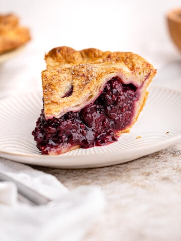 A slice of blackberry pie on a plate.