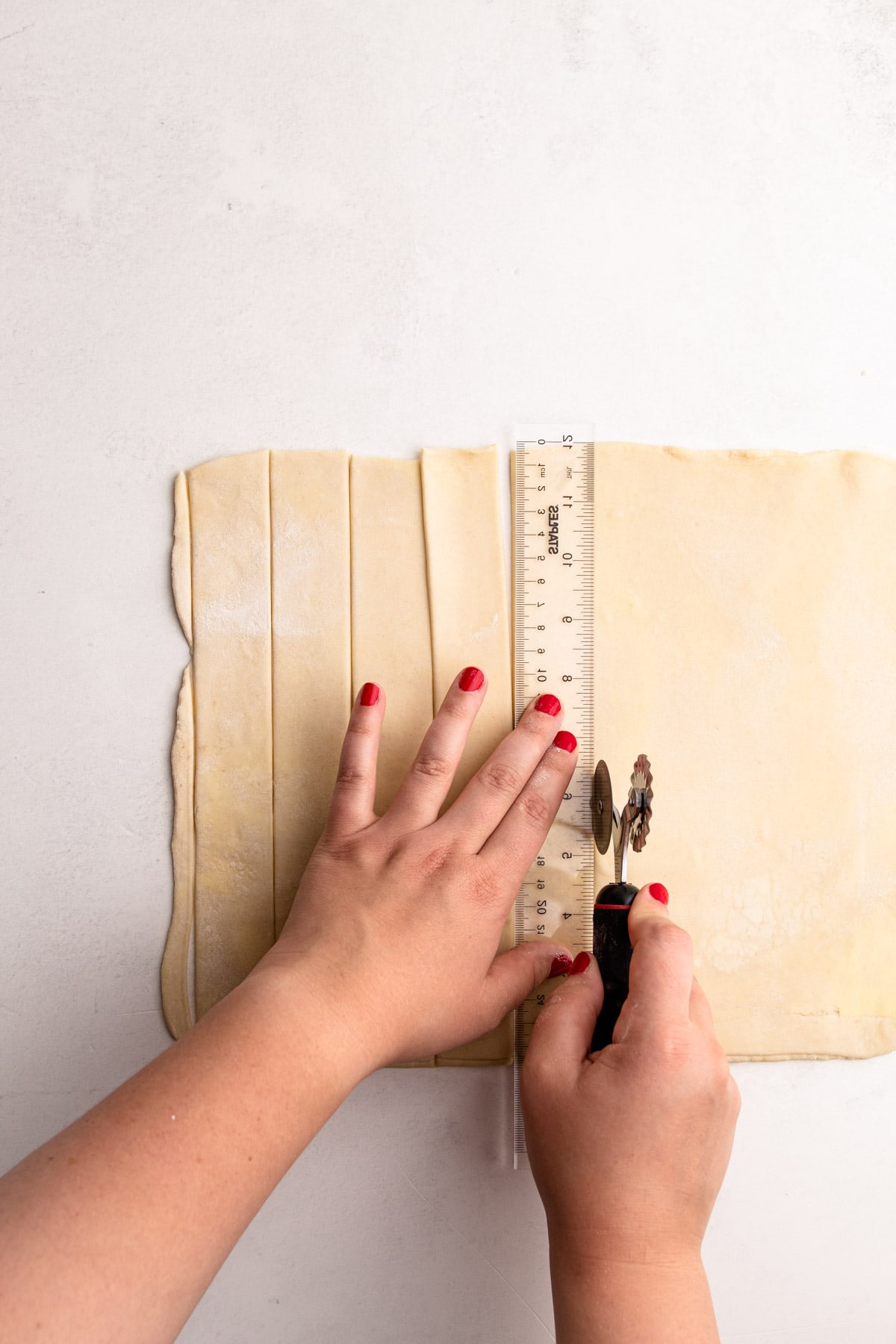 Cutting lattice strips from a flaky pie crust.