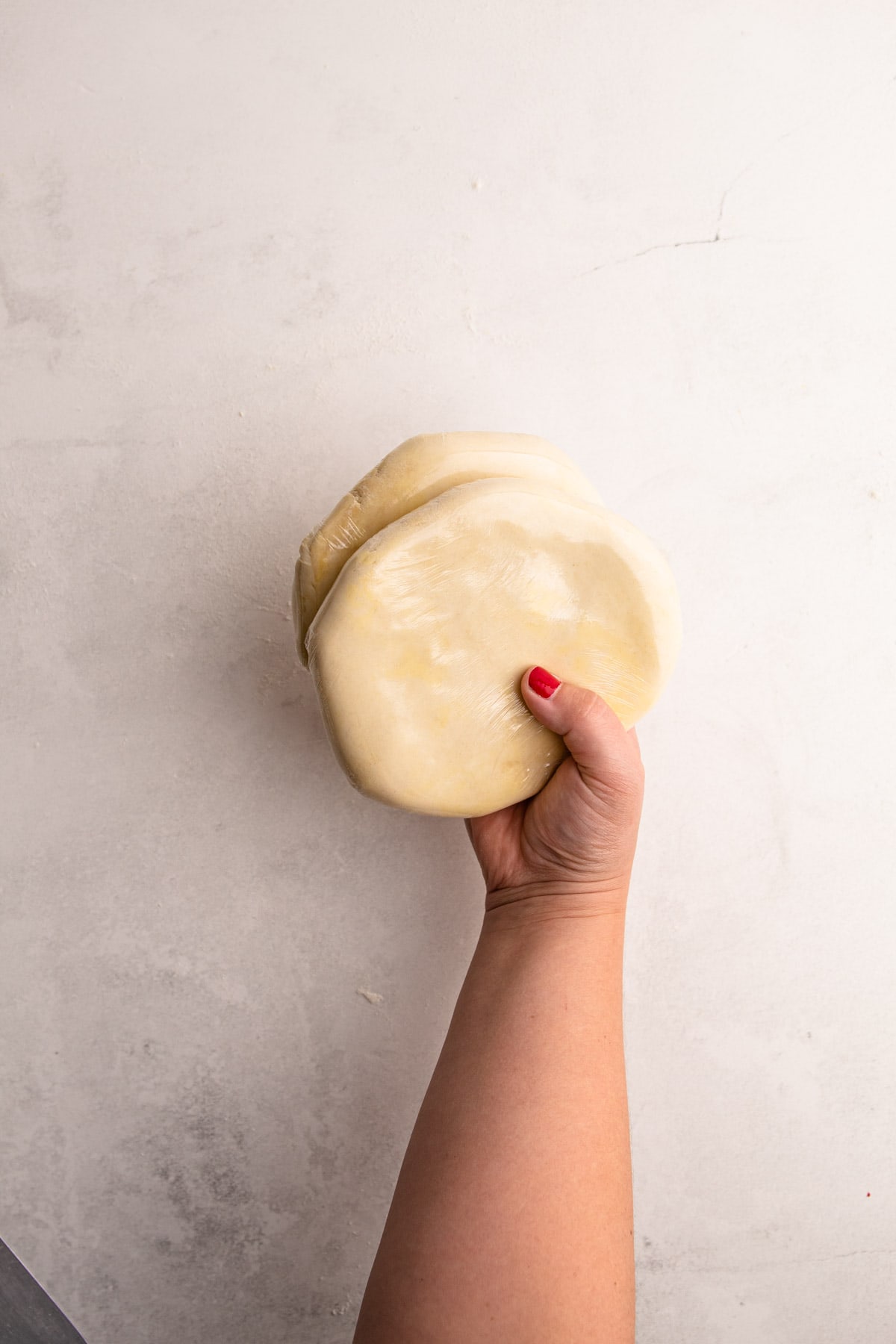 Two pie flaky pie dough disks wrapped in plastic.