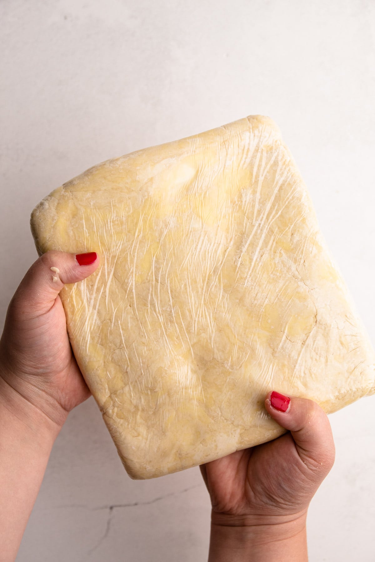 A rectangle of flaky pie dough wrapped in plastic.