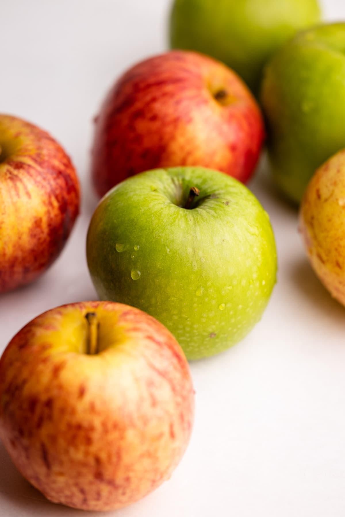 A mix of apples on a white surface.