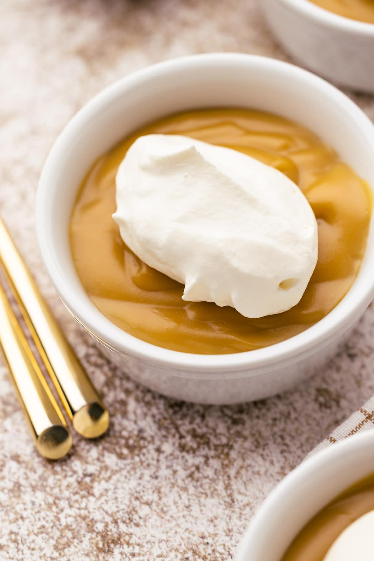 A bowl of butterscotch pudding with whipped cream on top.