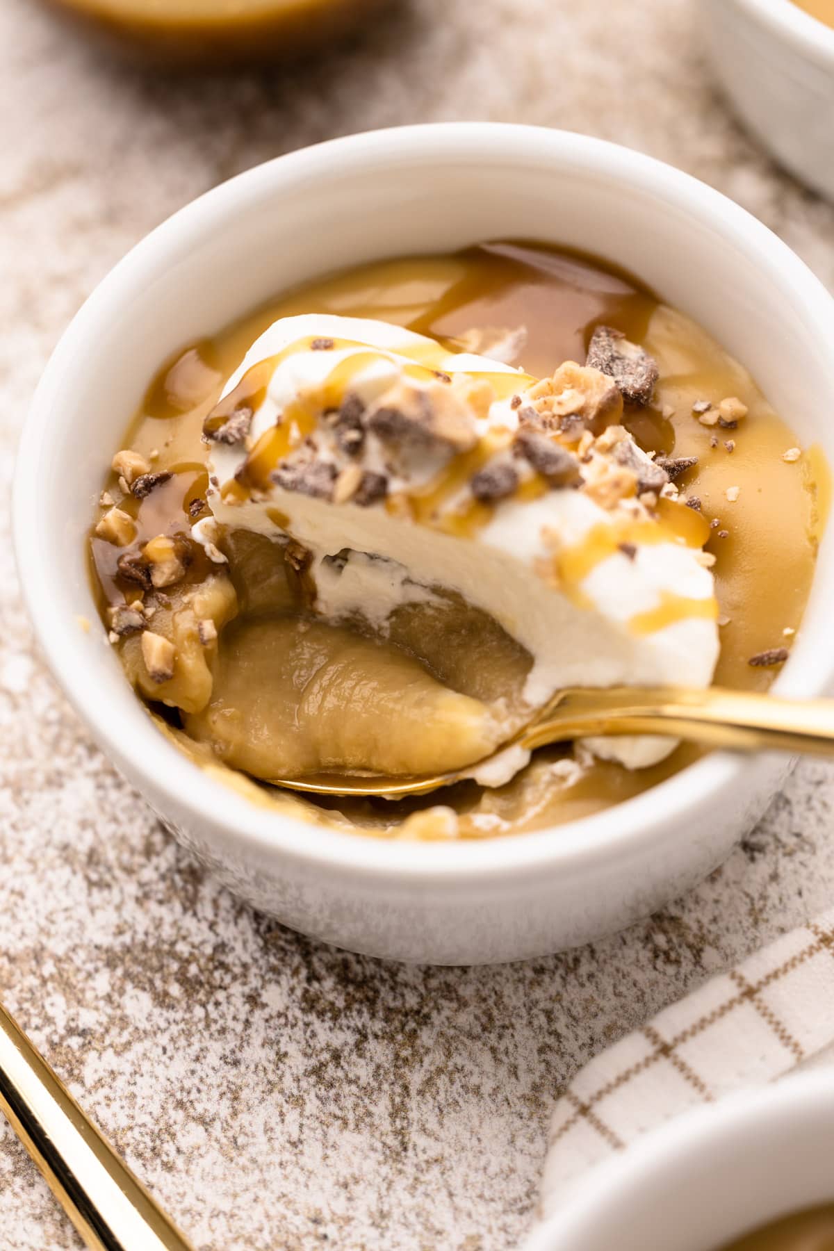 A bowl of butterscotch pudding with chocolate toffee pieces on top.