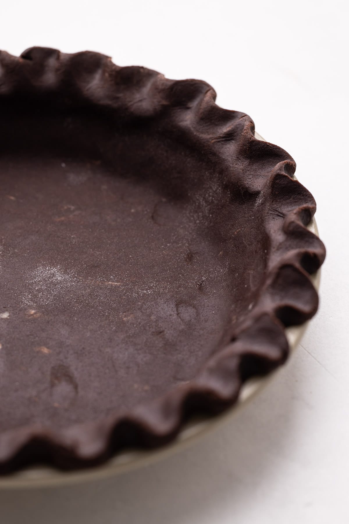 Chocolate pie crust crimped in a pie plate.