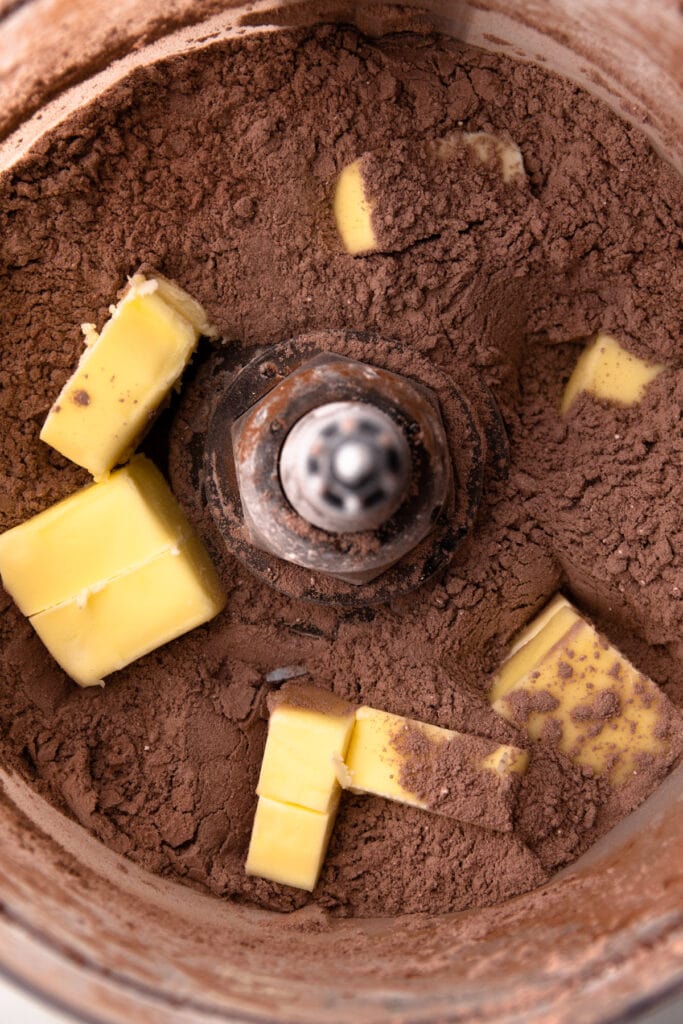 Making chocolate pie crust in a food processor with chunks of butter.