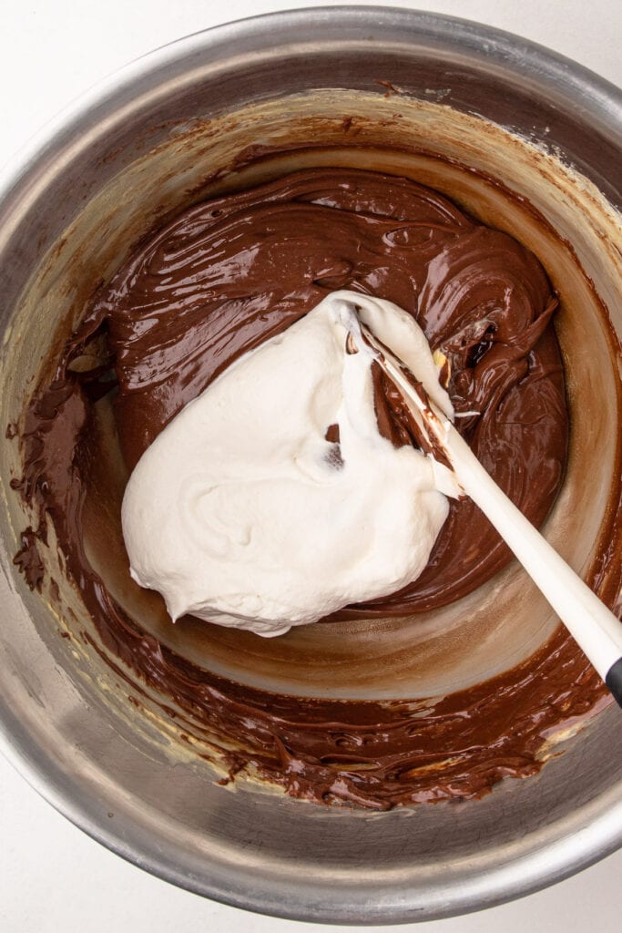 Adding whipped cream into chocolate silk pie filling.